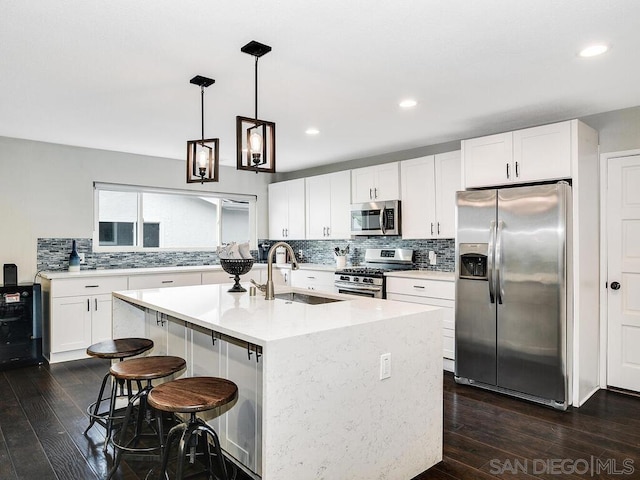 kitchen featuring sink, stainless steel appliances, white cabinets, and a center island with sink