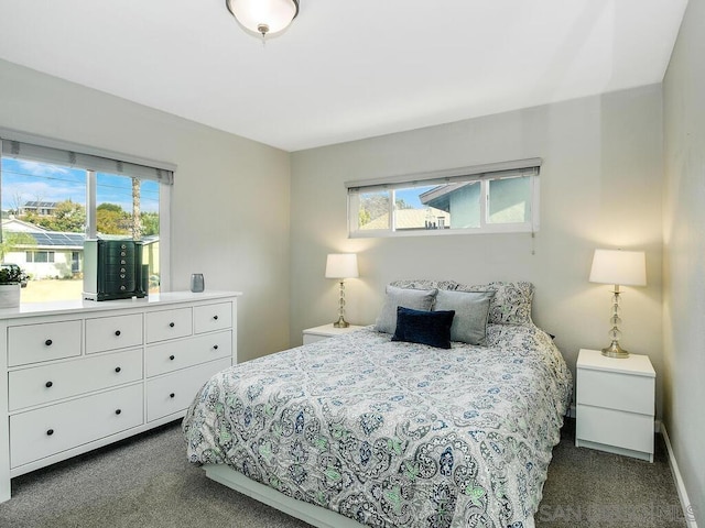 bedroom featuring dark carpet and multiple windows