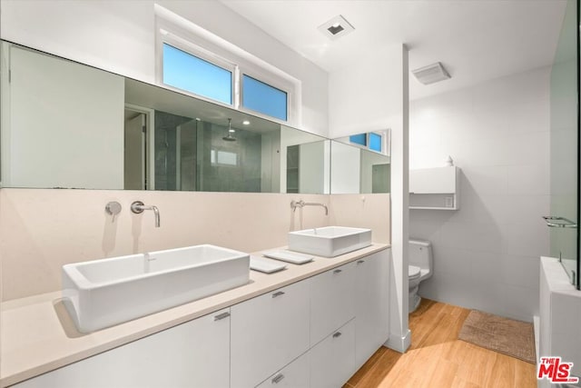 bathroom featuring vanity, hardwood / wood-style flooring, toilet, and walk in shower