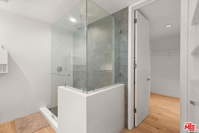 bathroom with hardwood / wood-style floors and a tile shower