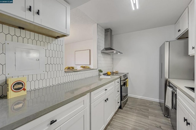 kitchen featuring tasteful backsplash, appliances with stainless steel finishes, white cabinets, and wall chimney exhaust hood