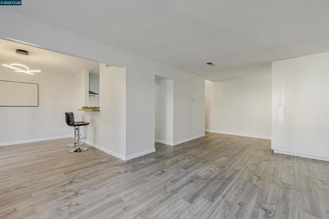 unfurnished room with a textured ceiling and light wood-type flooring