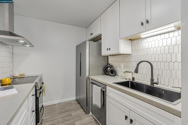 kitchen featuring white cabinets, stainless steel appliances, sink, and wall chimney range hood