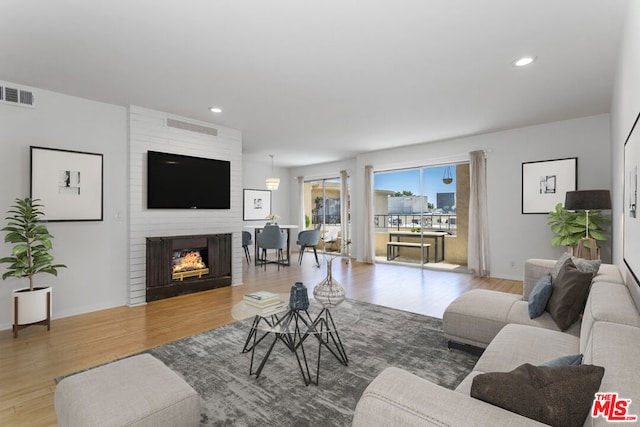 living room with wood-type flooring and a large fireplace