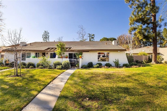 view of front facade featuring stucco siding, a front lawn, a gate, fence, and a chimney