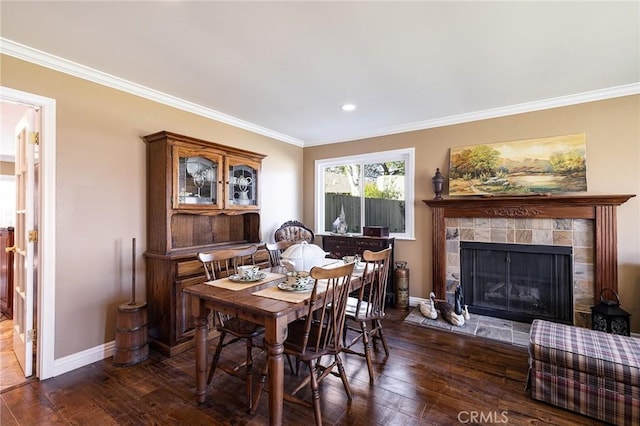 dining area with crown molding, a tile fireplace, and dark hardwood / wood-style floors