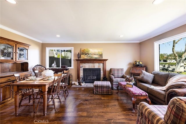 living room featuring dark hardwood / wood-style flooring, a tiled fireplace, and crown molding