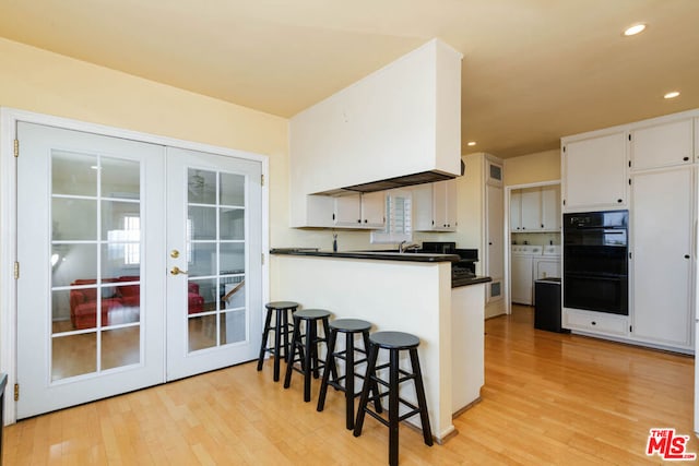 kitchen with french doors, white cabinetry, separate washer and dryer, kitchen peninsula, and double oven