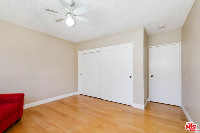 unfurnished bedroom with ceiling fan, wood-type flooring, a closet, and a textured ceiling