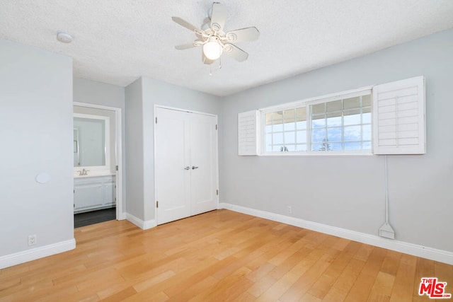 unfurnished bedroom featuring sink, light hardwood / wood-style floors, a closet, and a textured ceiling