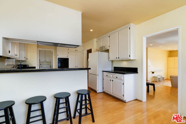 kitchen featuring light hardwood / wood-style flooring, white cabinetry, white refrigerator, kitchen peninsula, and oven