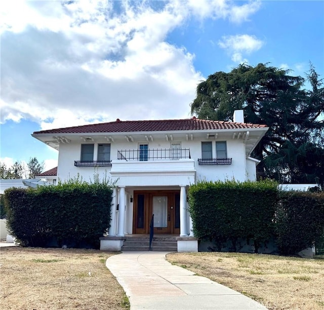 view of front of property with a balcony and a front lawn