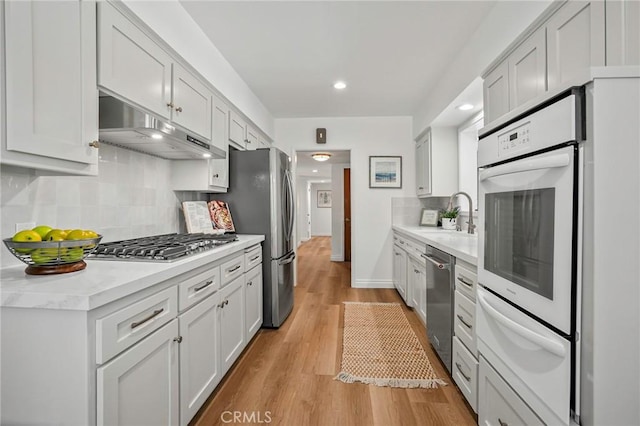 kitchen with sink, light hardwood / wood-style flooring, white cabinets, and appliances with stainless steel finishes