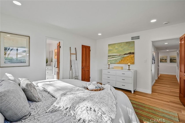 bedroom featuring ensuite bath and light hardwood / wood-style flooring