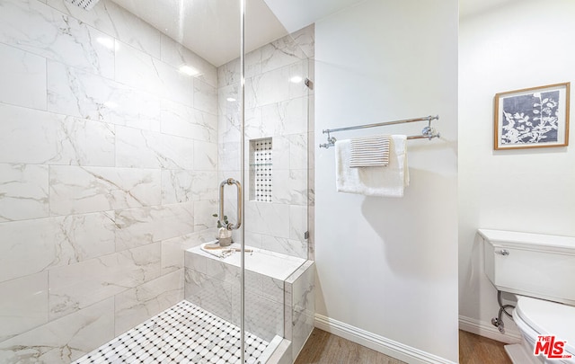 bathroom featuring hardwood / wood-style floors, a shower with door, and toilet