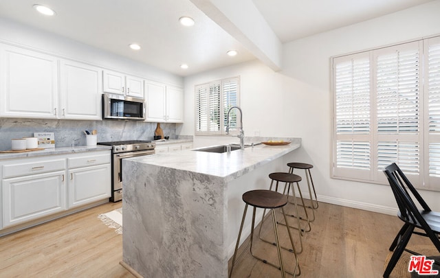 kitchen with sink, a kitchen breakfast bar, white cabinets, and appliances with stainless steel finishes