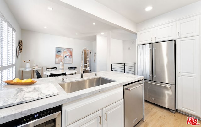 kitchen featuring stainless steel appliances, white cabinetry, sink, and light hardwood / wood-style flooring