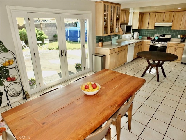 kitchen with tasteful backsplash, dishwasher, light tile patterned flooring, and stainless steel range oven