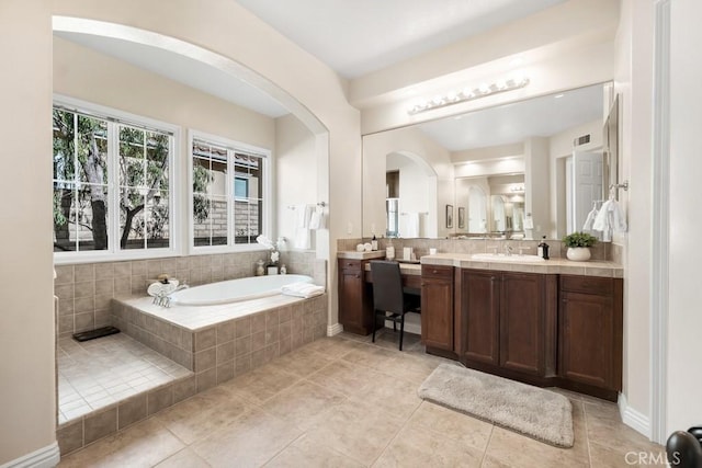 bathroom with vanity, tiled tub, and tile patterned flooring