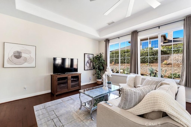 living room featuring ceiling fan, a tray ceiling, and dark hardwood / wood-style flooring