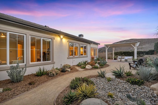 property exterior at dusk featuring a pergola and a patio area