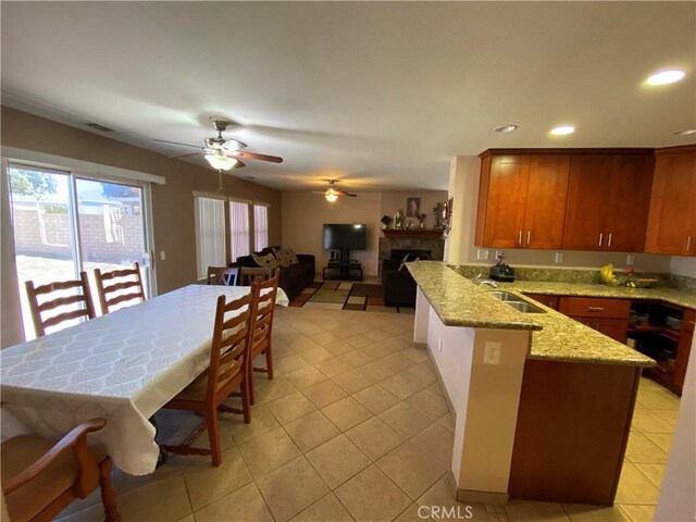 kitchen featuring kitchen peninsula, sink, light stone countertops, and light tile patterned floors