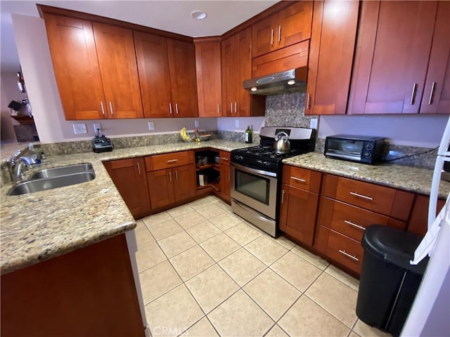 kitchen featuring light stone countertops, sink, light tile patterned floors, and stainless steel gas stove