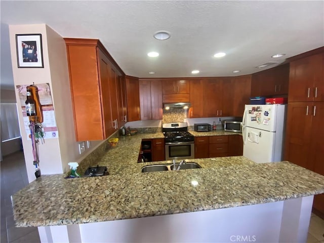 kitchen with light stone countertops, appliances with stainless steel finishes, extractor fan, and kitchen peninsula