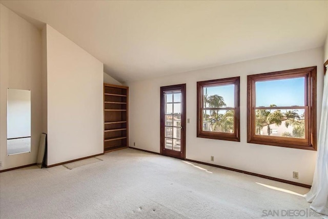 empty room with vaulted ceiling and light carpet