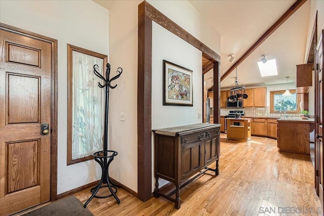 interior space with lofted ceiling with skylight and light hardwood / wood-style flooring