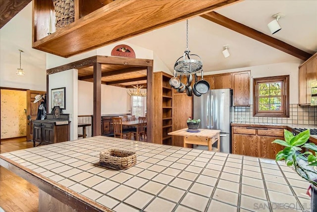 kitchen featuring hanging light fixtures, tile countertops, and stainless steel fridge