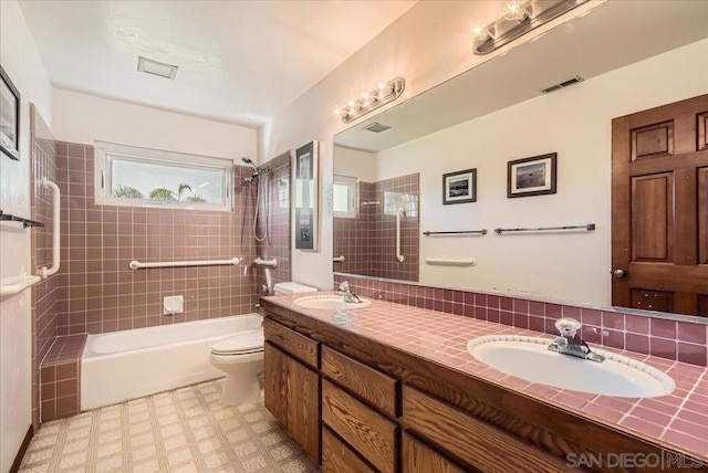 full bathroom with tiled shower / bath, vanity, toilet, and decorative backsplash