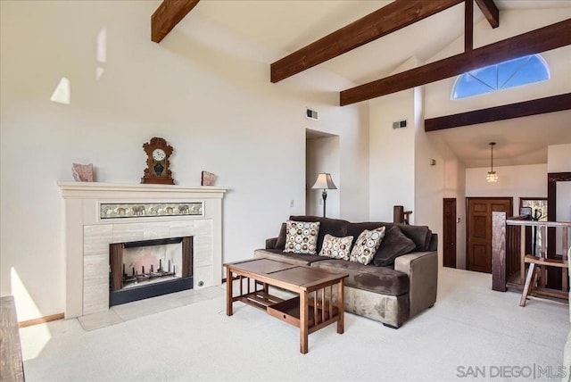 living room with light colored carpet, beam ceiling, a tiled fireplace, and high vaulted ceiling