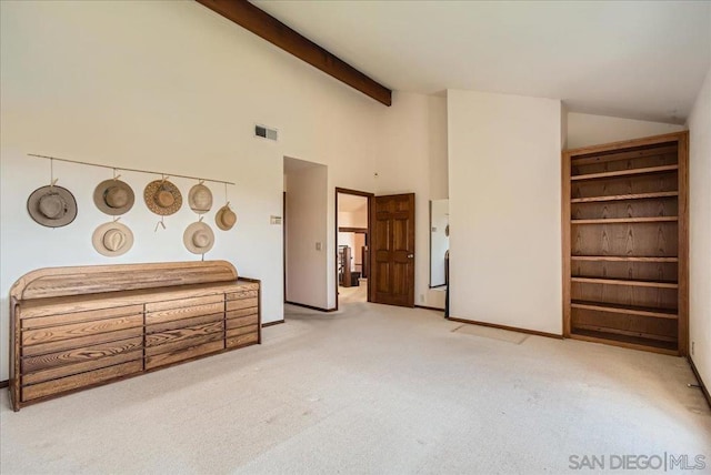 unfurnished bedroom with beamed ceiling, light carpet, and high vaulted ceiling