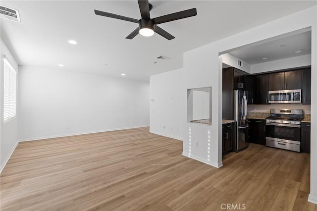 kitchen featuring stainless steel appliances, ceiling fan, light stone counters, and light wood-type flooring