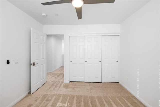 unfurnished bedroom with light colored carpet, a closet, and ceiling fan