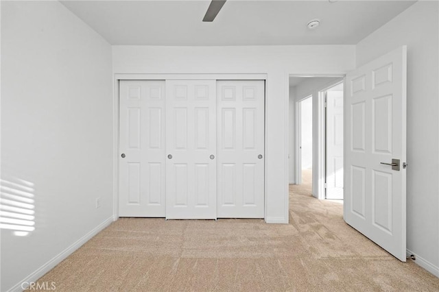 unfurnished bedroom featuring ceiling fan, light colored carpet, and a closet