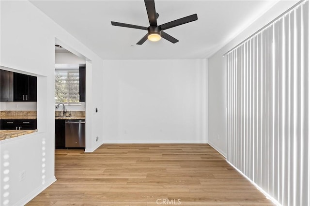 unfurnished living room featuring ceiling fan, sink, and light wood-type flooring