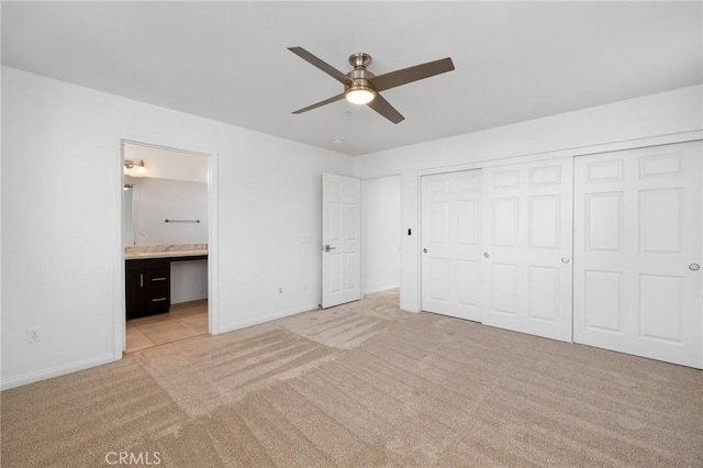 unfurnished bedroom featuring ceiling fan, light carpet, ensuite bath, and a closet