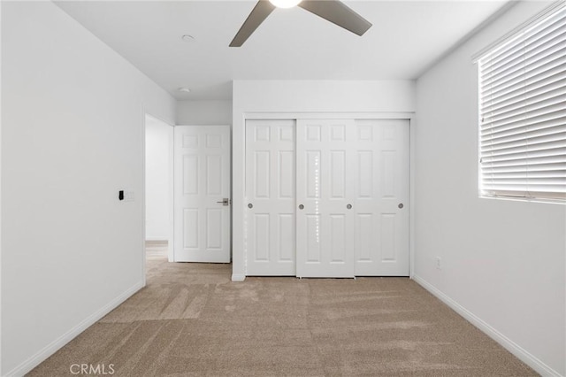 unfurnished bedroom with multiple windows, light carpet, ceiling fan, and a closet