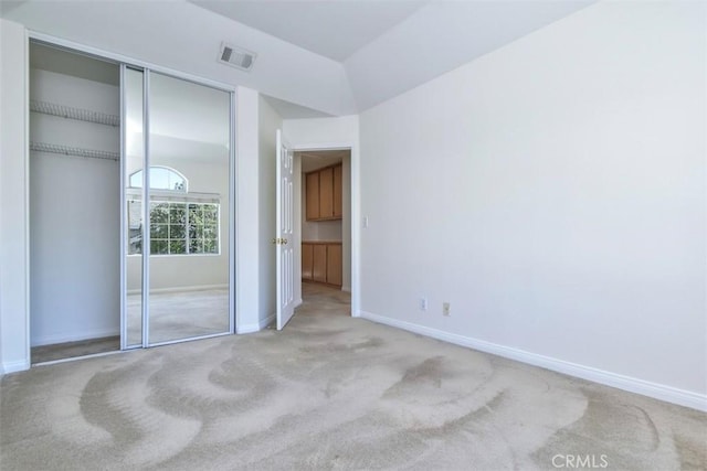 unfurnished bedroom with light colored carpet and a closet