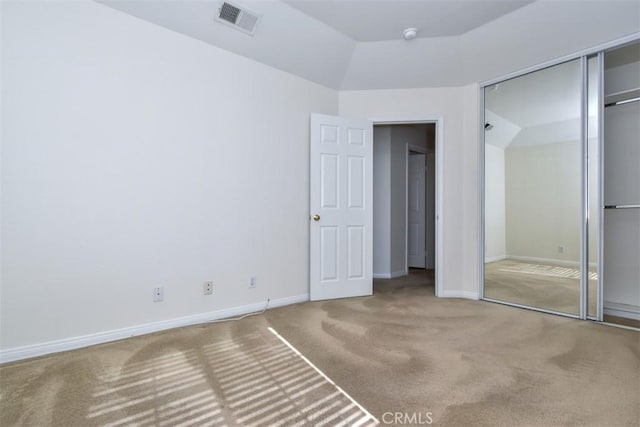 unfurnished bedroom featuring vaulted ceiling, a closet, and carpet