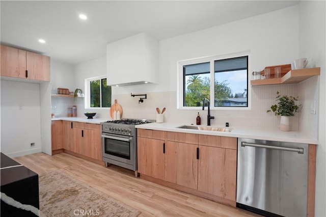 kitchen with sink, light brown cabinets, light hardwood / wood-style floors, and appliances with stainless steel finishes