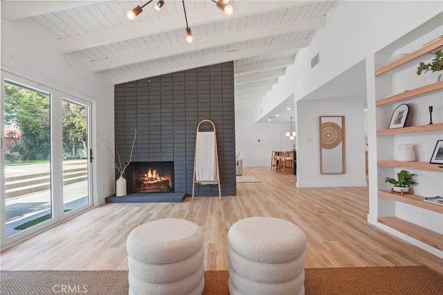 living room with wood ceiling, light hardwood / wood-style flooring, built in features, vaulted ceiling with beams, and a brick fireplace