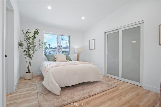 bedroom with lofted ceiling and light wood-type flooring