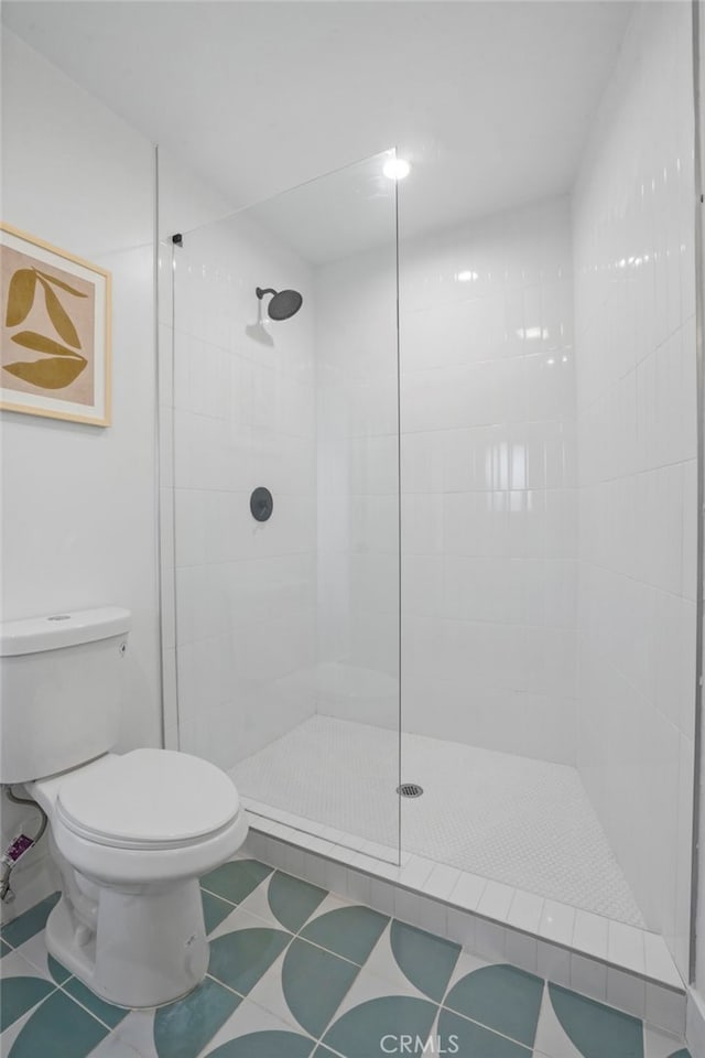 bathroom with toilet, tile patterned flooring, and a tile shower