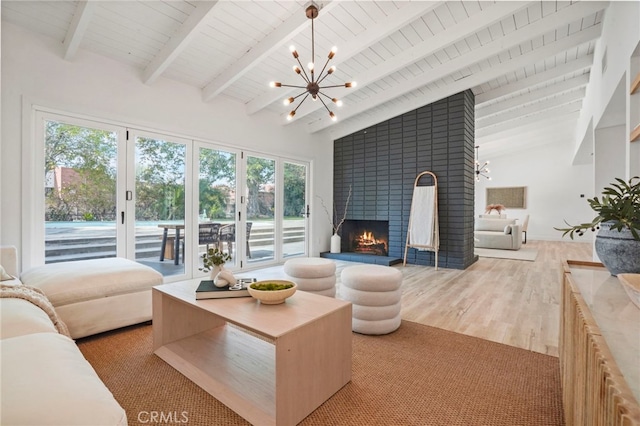 living room featuring wood ceiling, a fireplace, lofted ceiling with beams, a chandelier, and light wood-type flooring