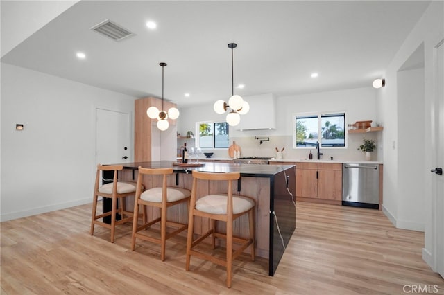 kitchen featuring hanging light fixtures, sink, stainless steel dishwasher, and light hardwood / wood-style floors