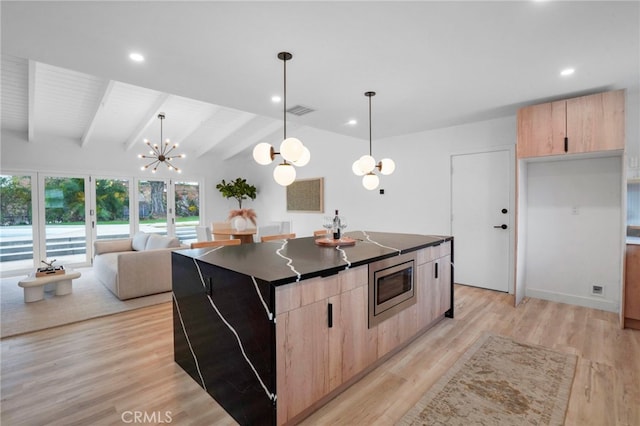 kitchen with light hardwood / wood-style flooring, vaulted ceiling with beams, a center island, stainless steel microwave, and decorative light fixtures