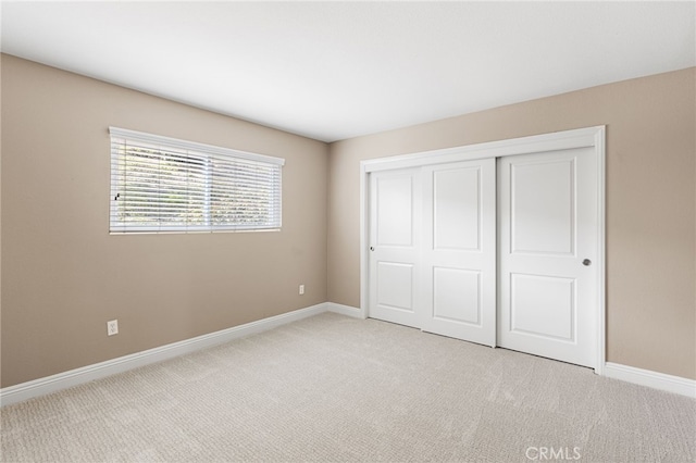 unfurnished bedroom featuring light carpet and a closet